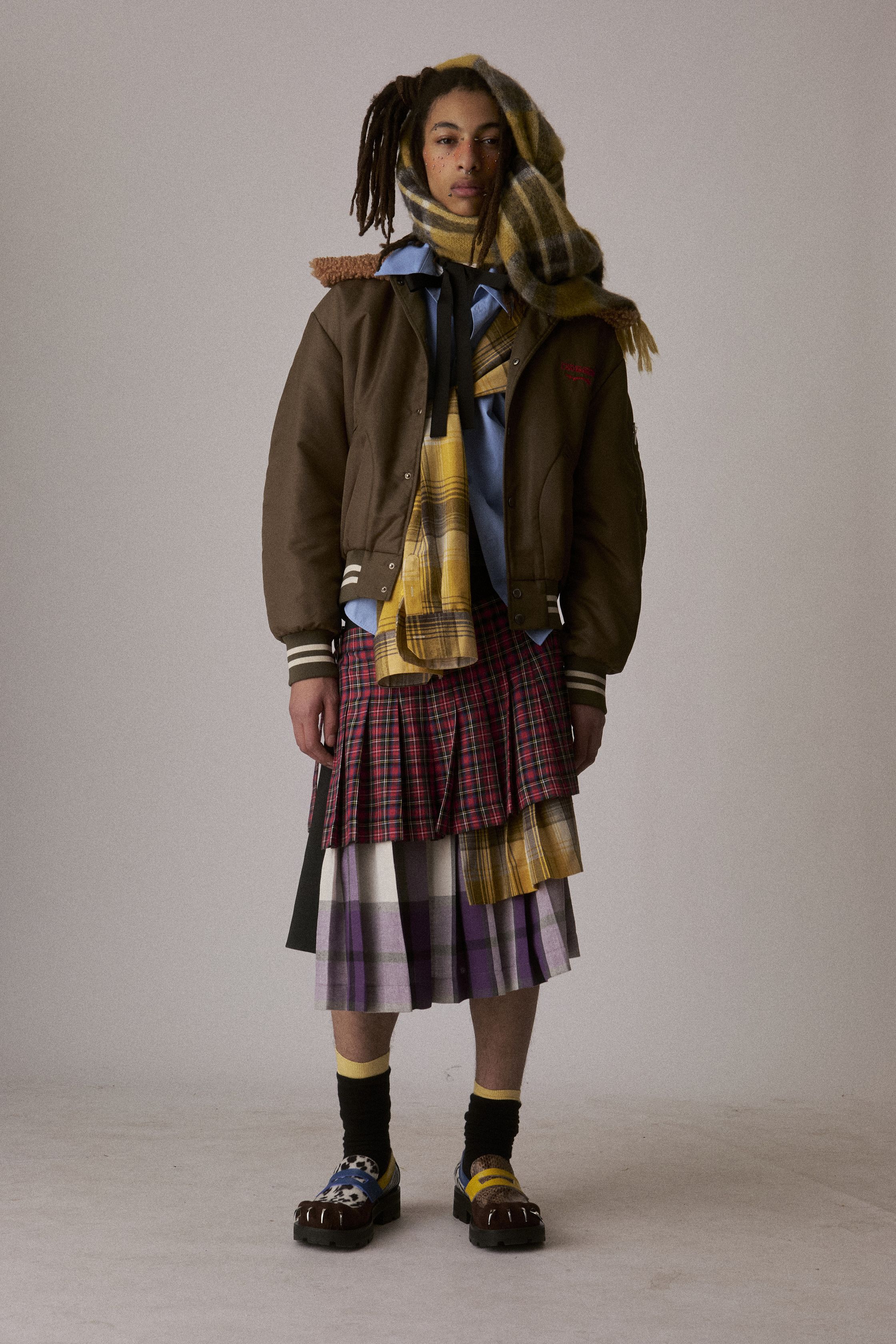 Charles Jeffrey Loverboy 2026秋冬继续以“童话式反叛”挑战性别与规范，苏格兰格纹、手工针织、玩偶配饰与夸张头饰构成近乎戏剧化的造型语言。服装在稚拙与暗黑之间游走，像一场带有朋克精神的成人童话，表达边缘身份的自我认同与情绪释放。这不是可被轻易驯化的时装，而是一种对主流秩序的持续挑衅-顽石频道趋势研究